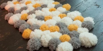 Colorful homemade yarn pom-pom rug displayed in a living room setting.